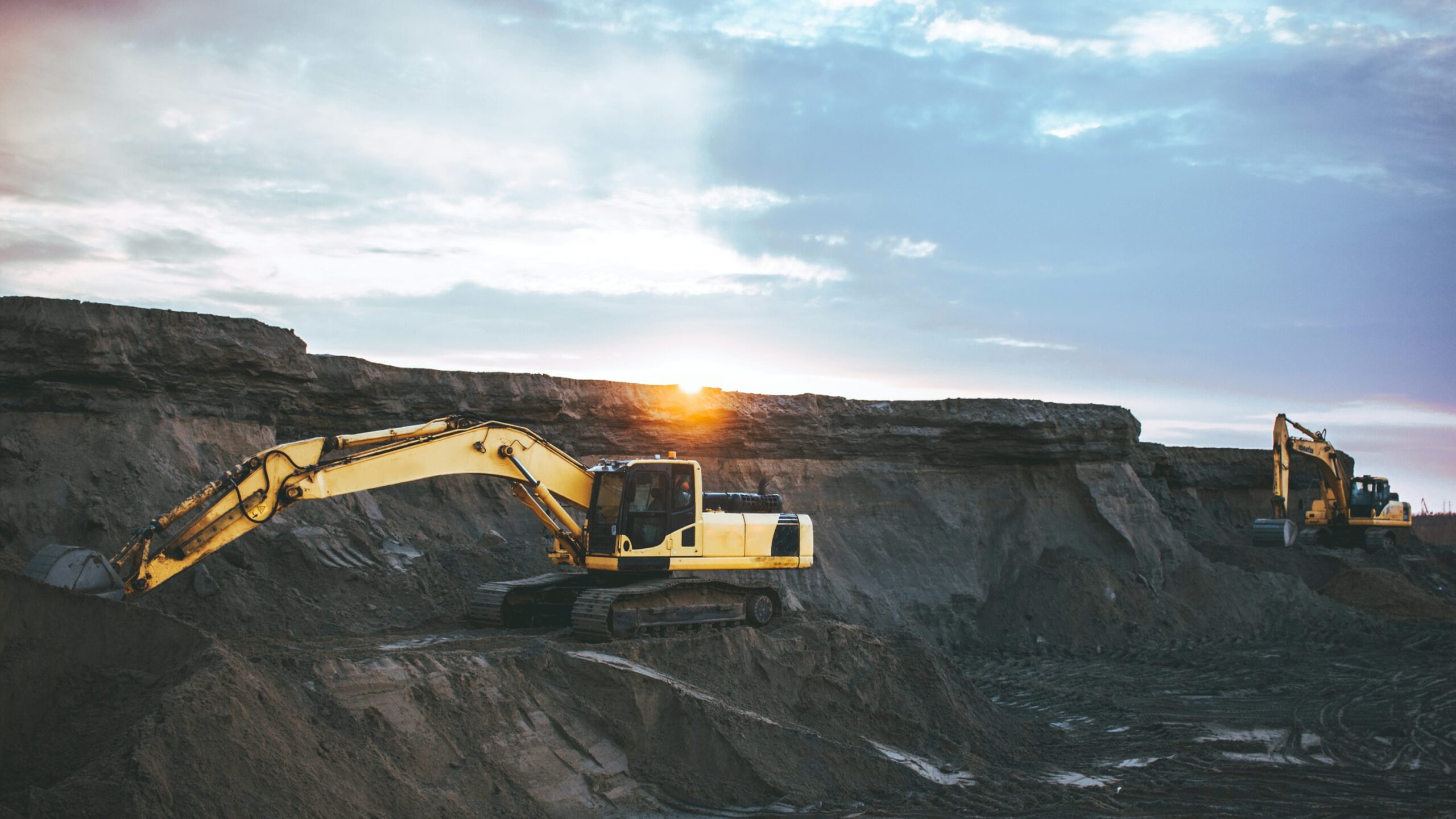 Hydraulic excavators working in a quarry at sunset