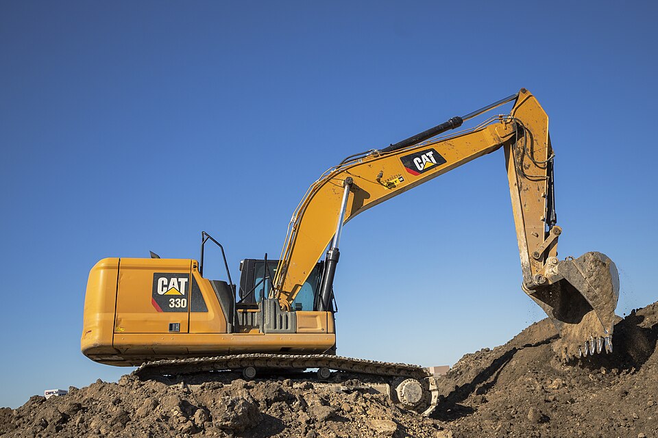 Caterpillar 330 excavator on an earthworks site beneath a clear blue sky